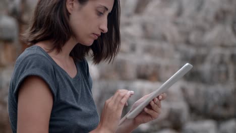 Mädchen-Mit-Computer-Tablet-An-Einem-Wunderschönen-Felsigen-Strand,-Nahaufnahme,-Zeitlupe