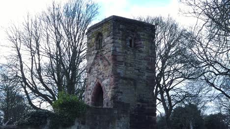 Historic-Windleshaw-Chantry-stonework-tower-exterior-slow-motion-around-woodland-ruins-against-blue-sky