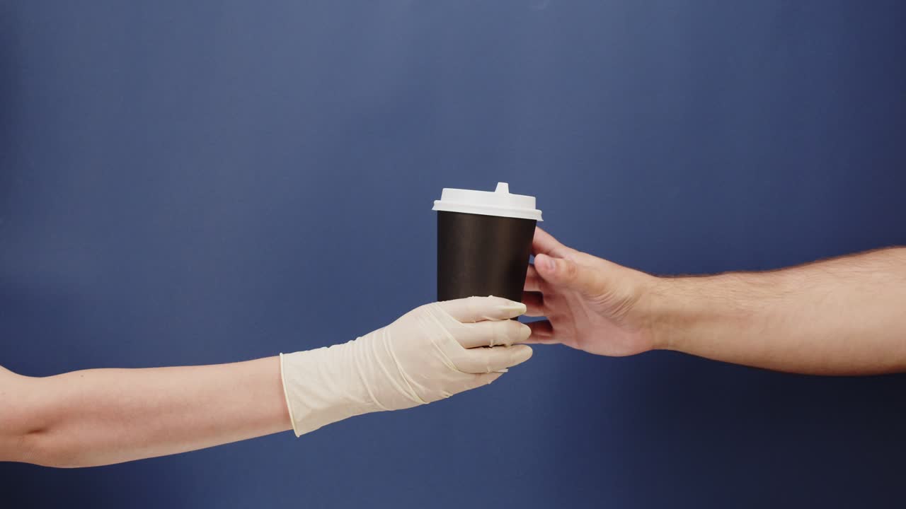 Mão Enluvada Entregando Copo de Café Descartável para Outra Mão