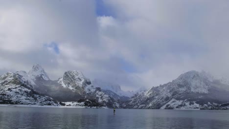 Hombre-En-Paddle-Board-Entre-El-Agua-Y-Las-Montañas-En-La-Costa