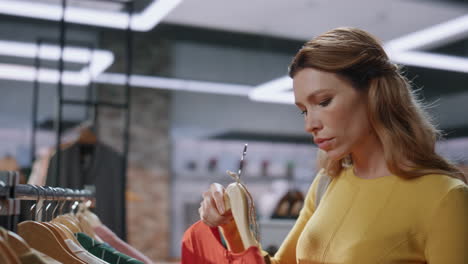 mujer cliente mirando precios eligiendo ropa en una boutique de primer plano. señora compradora