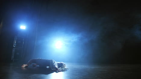 una mujer con un vestido blanco está bailando en el escenario los bailes dramáticos del ballet moderno. una bailarina de ballet mueve plástico realizando una coreografía moderna en humo.