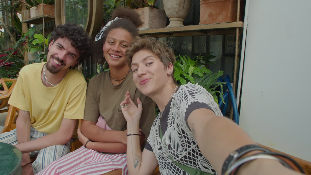 Amigos alegres conversando na câmera em um café ao ar livre