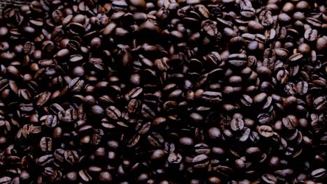 Coffee-beans-are-falling-and-forming-a-stack,-many-of-grains-are-in-free-fall,-captured-into-indoor-environment