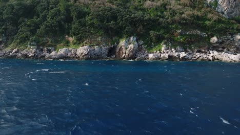 costa rocosa con una cueva cerca de capri, italia con exuberante vegetación y mar azul profundo, vista aérea