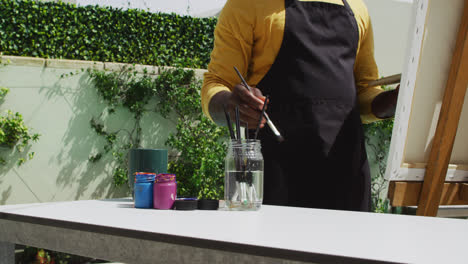 Afroamerikanischer-älterer-Mann,-Der-Auf-Einer-Terrasse-Steht-Und-Malt