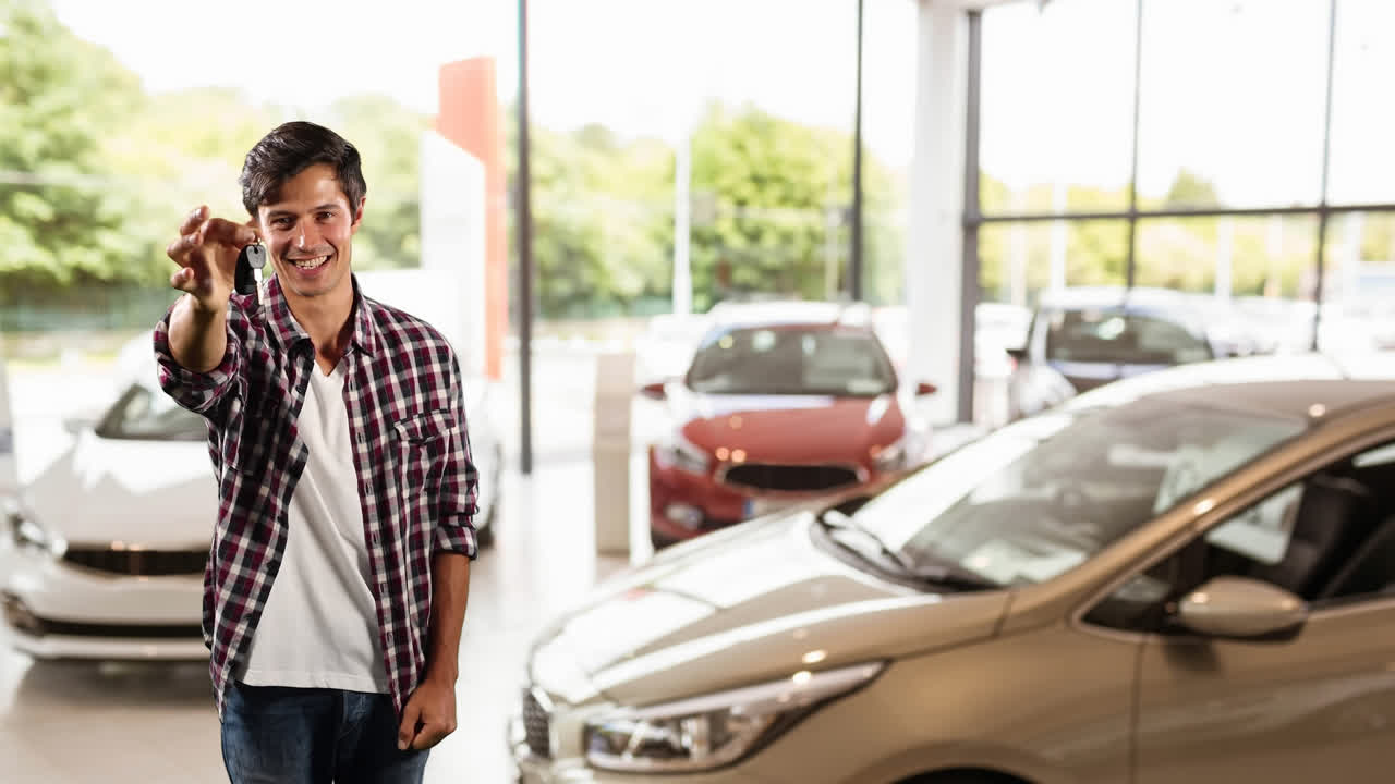 hombre caucásico mostrando las llaves de sus coches en un distribuidor de coches, pareciendo feliz