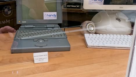 a collection of vintage apple computers alongside a toy robot in a display case.
