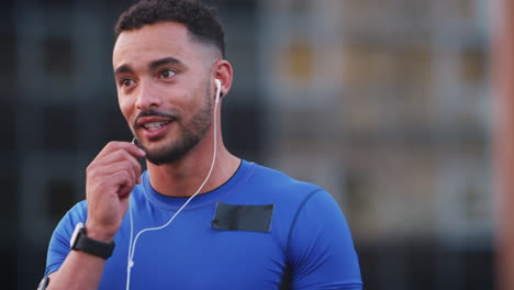 male runner using smartphone headphones talking in street