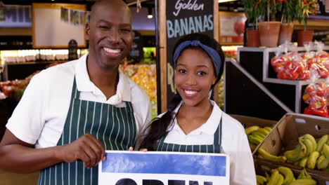 smiling staffs holding open signboard in organic section