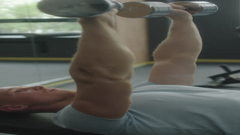 man doing dumbbell press on gym bench