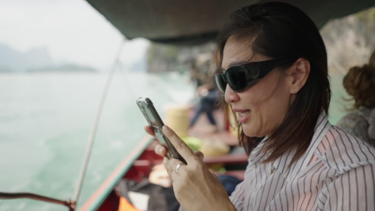 Woman on a boat interacting with her mobile phone during a scenic water journey