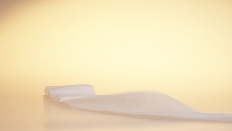 a toilet paper roll dropped on the floor and rolling forward against yellow background, object concept shot