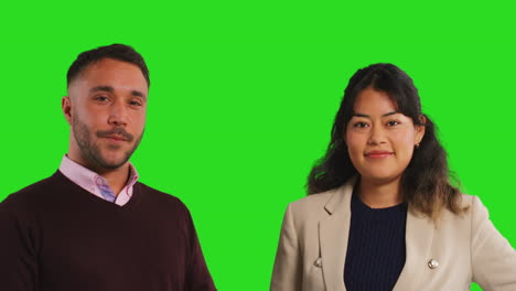 Close-Up-Studio-Portrait-Of-Male-And-Female-Teachers-Or-Businesspeople-Looking-At-Camera-Against-Green-Screen