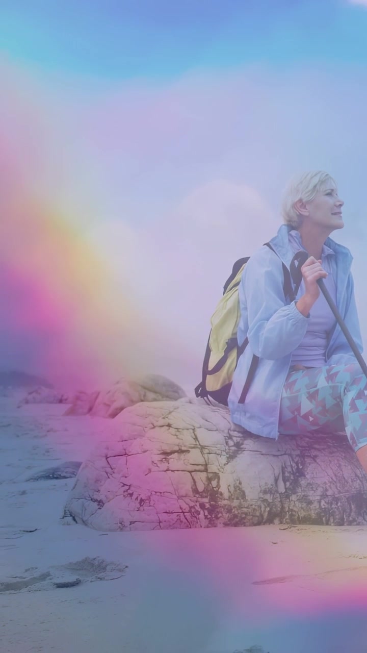 Video verticale: Donna seduta sulla costa con un palo che osserva l'orizzonte, la luce del sole che forma una foschia da viaggio.