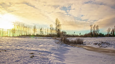time-lapse de nubes blancas que pasan sobre tierras de cultivo cubiertas de nieve en una fría mañana de invierno con el sol surgiendo en el fondo