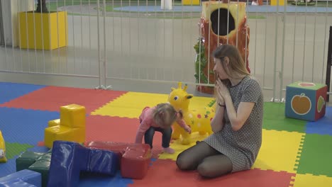 young mother plays with her little daughter in a playroom for children they laugh and marvel