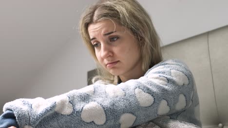 young woman feeling sad while sitting on bed