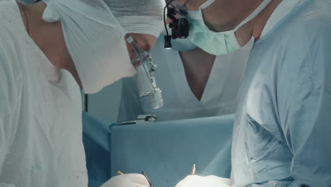 surgeon holds thread with micro forceps. experienced surgical team attaches grafted vessels on artery to divert blood supply in operating room