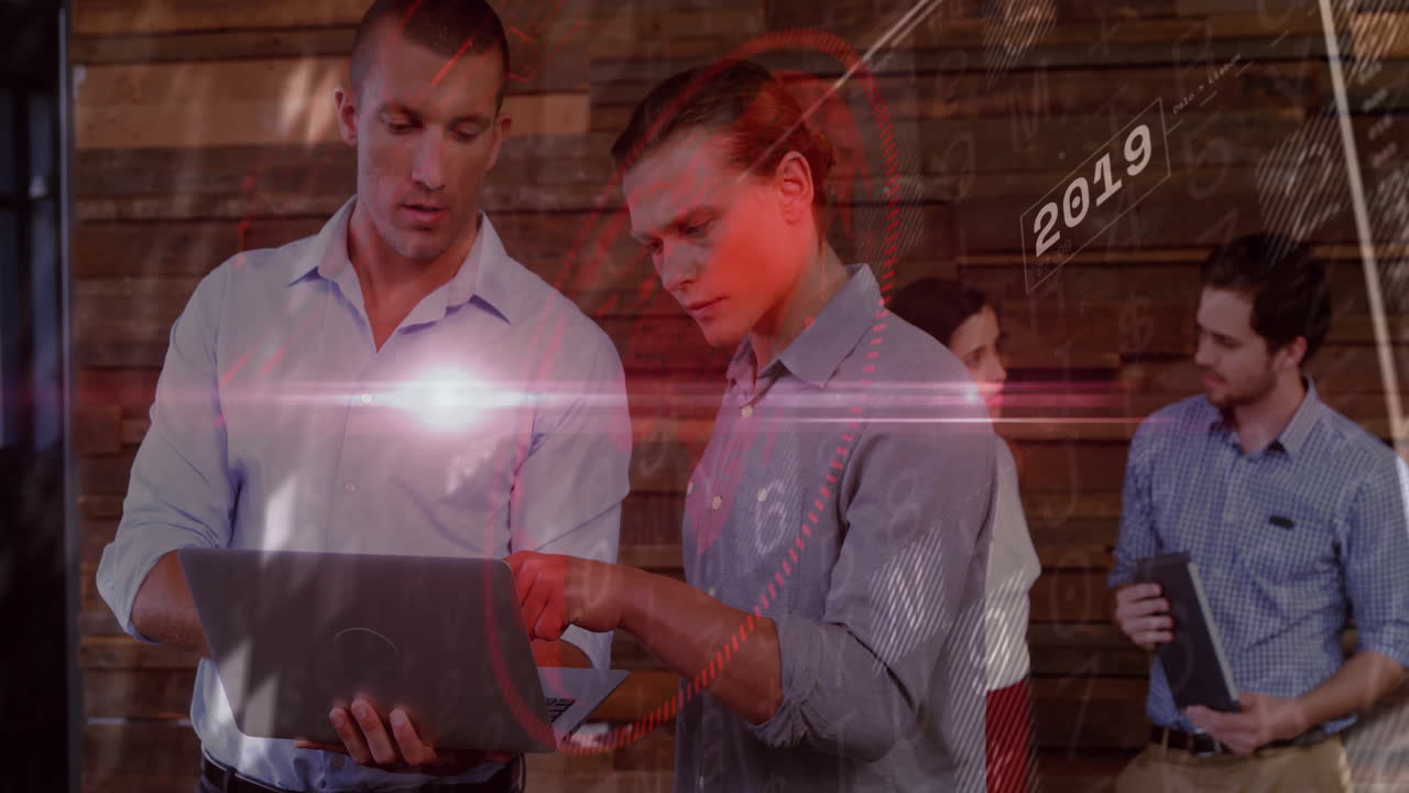 Business professionals discussing data on laptop with digital animation overlay