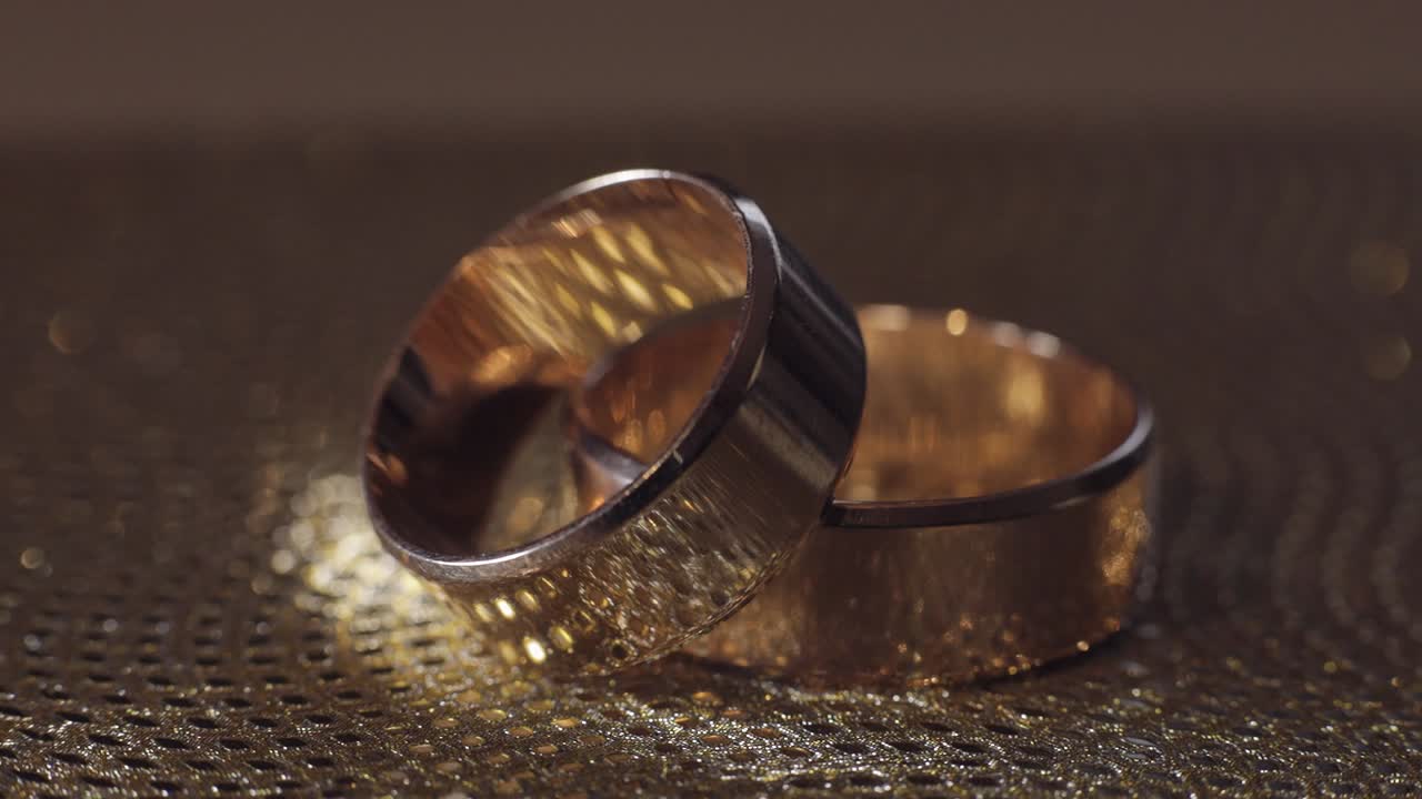 Wedding gold rings lying on shiny glossy surface. Shining with light. Close-up