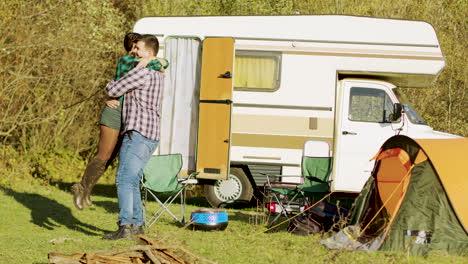 boyfriend spinning around her girlfriend in front of their retro camper van