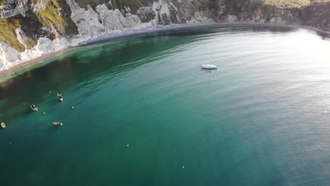 boats moored in tranquil turquoise waters at lulworth cove