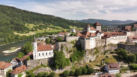 drone view of aarburg castle, church, and aare river surrounded by swiss hills and town buildings