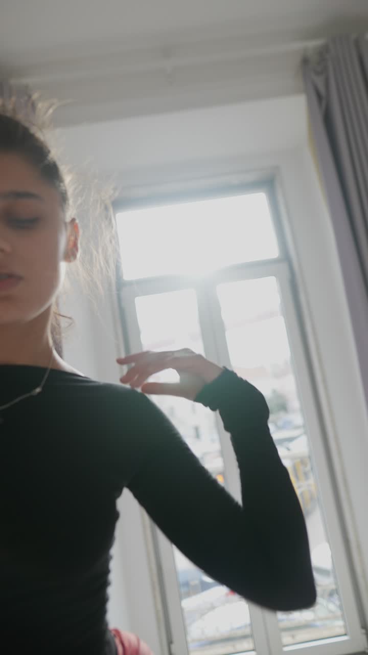 mujer practicando yoga en un dormitorio cerca de una ventana