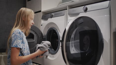 Una-Adolescente-Transfiere-Ropa-Limpia-De-La-Lavadora-A-La-Secadora