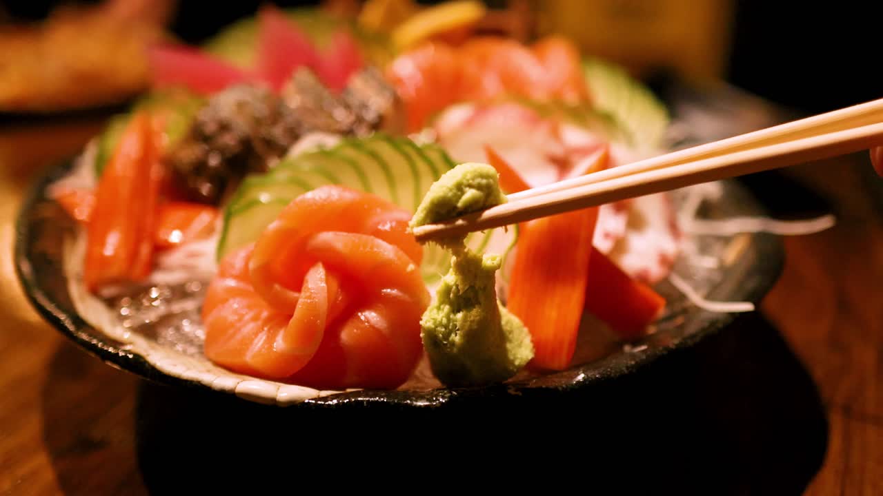Chopsticks picking wasabi from sashimi platter