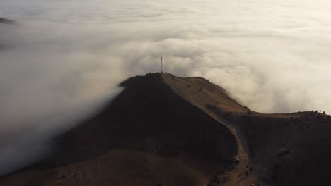 a mountain top surrounded entirely by a layer of clouds