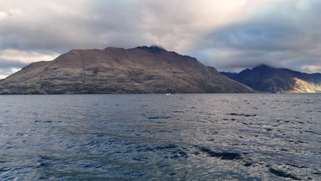 tranquil scenes of lake wakatipu in queenstown, new zealand, with mountains under dynamic cloud cover and soft lighting