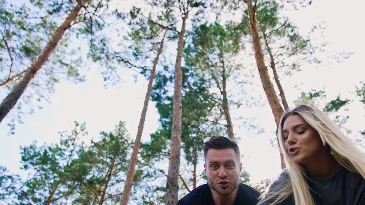 Young beautiful sportive couple playing with their newborn in the nature. Happy family of three having fun time together. Low angle view.
