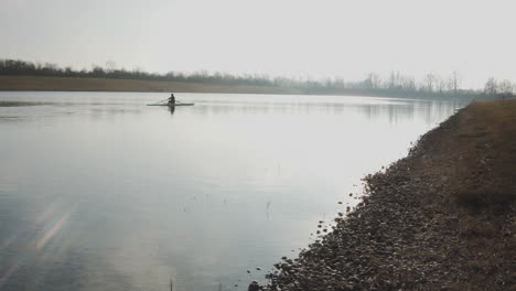 sporty rower trains on a moored canal on a sunny winter day