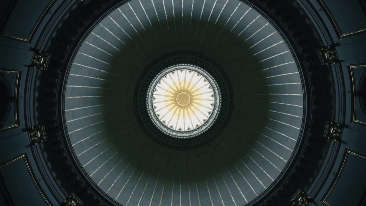Il lucernario centrale che reagisce allo sfarfallio dell'illuminazione nella rotonda, con rosetta dorata e costoloni radiali.