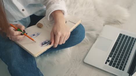 mujer joven dibujando y trabajando con una laptop