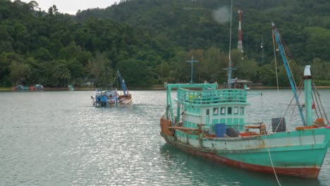 wooden fishing boat towing a sinking boat behind