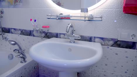 bathroom interior:  wash basin, tap, towel, bathtub with faucets and shower
