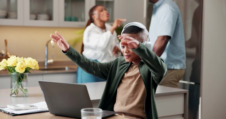 Young Boy Wearing Headphones Using Laptop and Celebrating Success at Home
