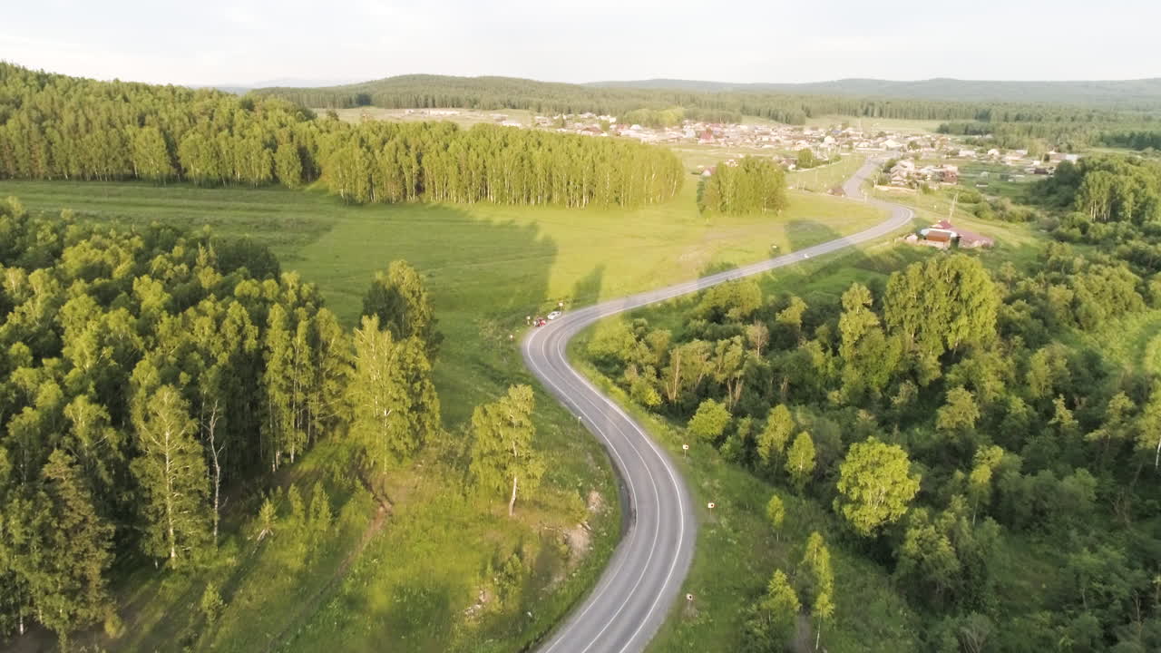 vista aérea de una carretera sinuosa a través de un bosque y un pueblo