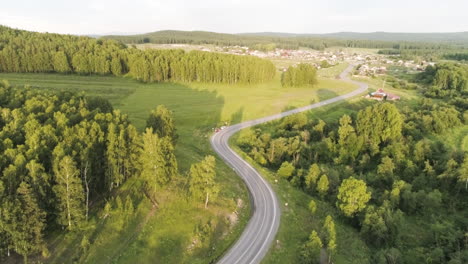 aerial view of a winding road through a forest and village