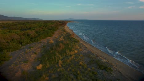 Imágenes-Cinematográficas-De-Drones-Aéreos-De-Gran-Altitud-Sobre-Una-Playa-De-Arena-Al-Atardecer-En-La-Costa-Azul-Cerca-De-Castiglione-En-El-Icónico-Parque-Natural-Maremma-En-Toscana,-Italia-Con-Olas,-Islas-Y-Un-Cielo-Dramático