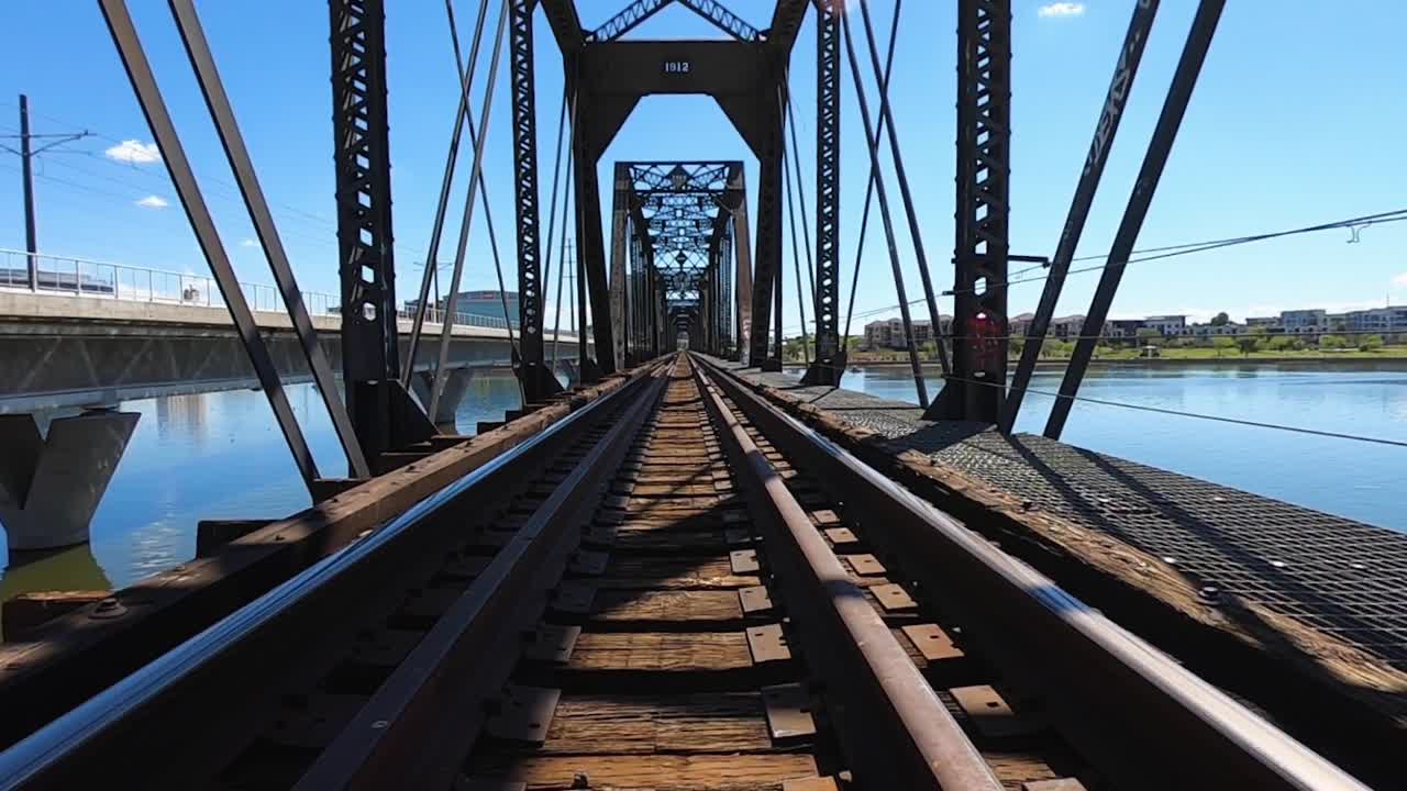 punto de vista viajando por las vías del tren mientras cruza un puente sobre el lago de la ciudad de tempe, tempe, arizona