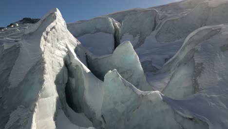 Sunlit-icy-peaks-in-a-glacier-in-the-Swiss-alps,-aerial-view