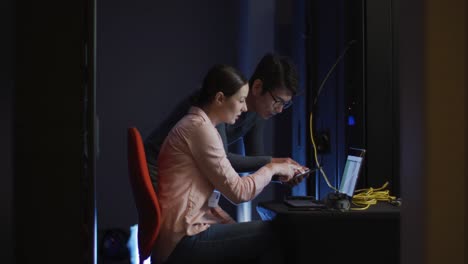 Diverse-male-and-female-it-technicians-using-laptop-checking-computer-server