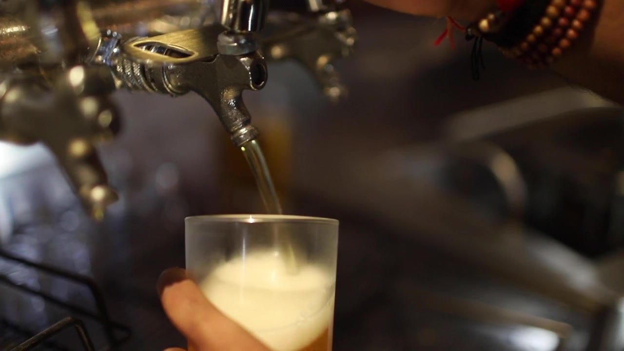Nærbilde av en person som tapper en halvliter øl på en bar eller nattklubb