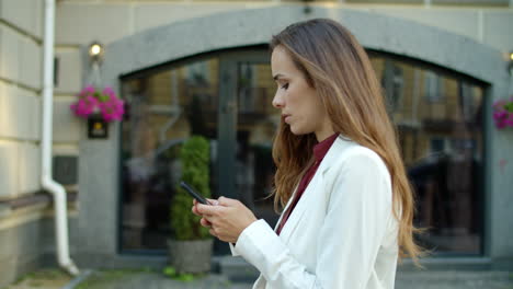 Thinking-business-woman-texting-message-on-mobile-phone-outdoors