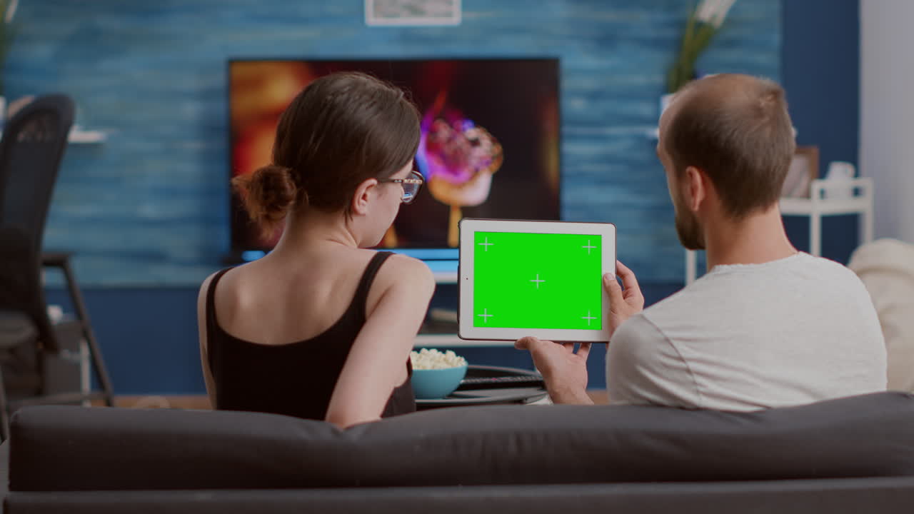 Man holding digital tablet with green screen watching online video content with girlfriend