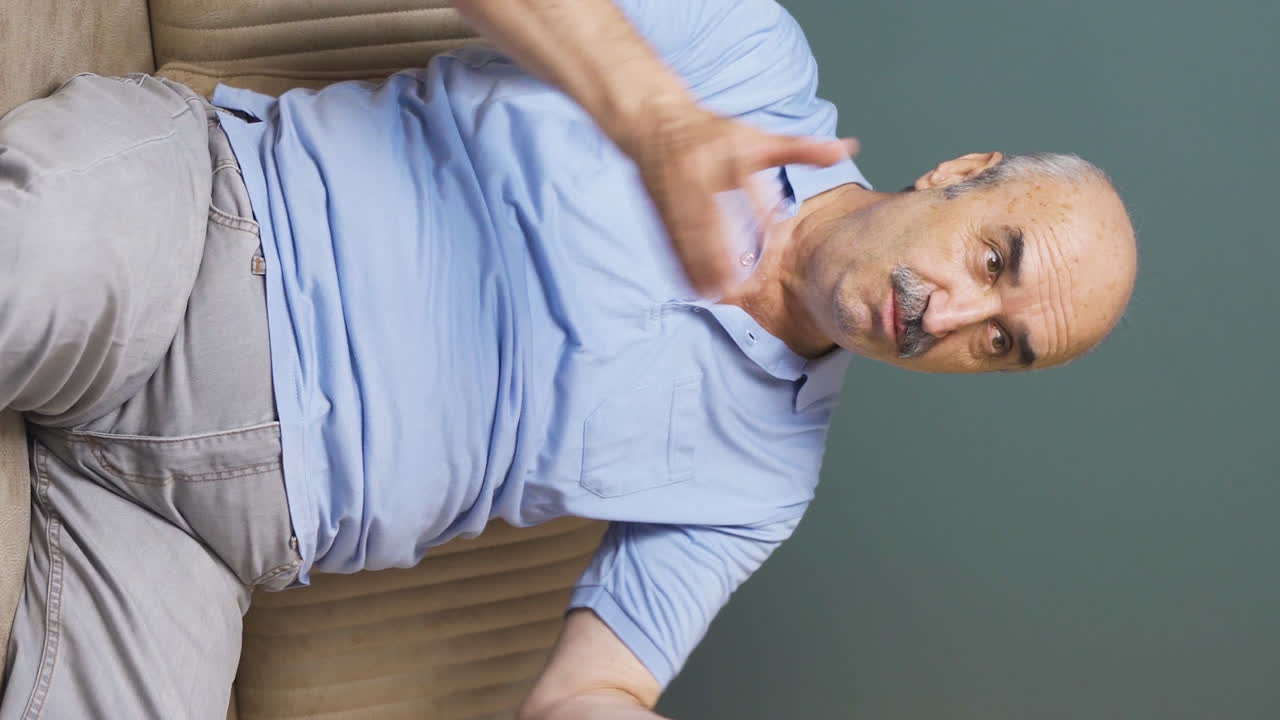 Vertikal video av den äldre mannen som gläds när han tittar på tv
